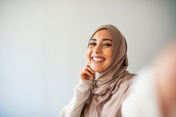 Muslim caucasian woman taking selfie. Happy beautiful woman with scarf take picture of her self using smartphone. A young beautiful and modern muslim woman taking selfie.