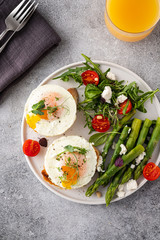 Toasts with asparagus and a fried egg on a white plate, top view, grey background.