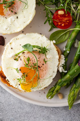 Toasts with asparagus and a fried egg on a white plate, top view, grey background.