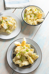 Potato salad with egg and mayonnaise on wooden background
