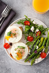 Toasts with asparagus and a fried egg on a white plate, top view, grey background.