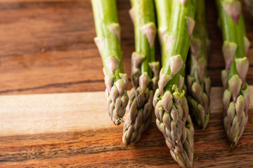 Bunch of fresh green asparagus spears on a rustic wooden table.