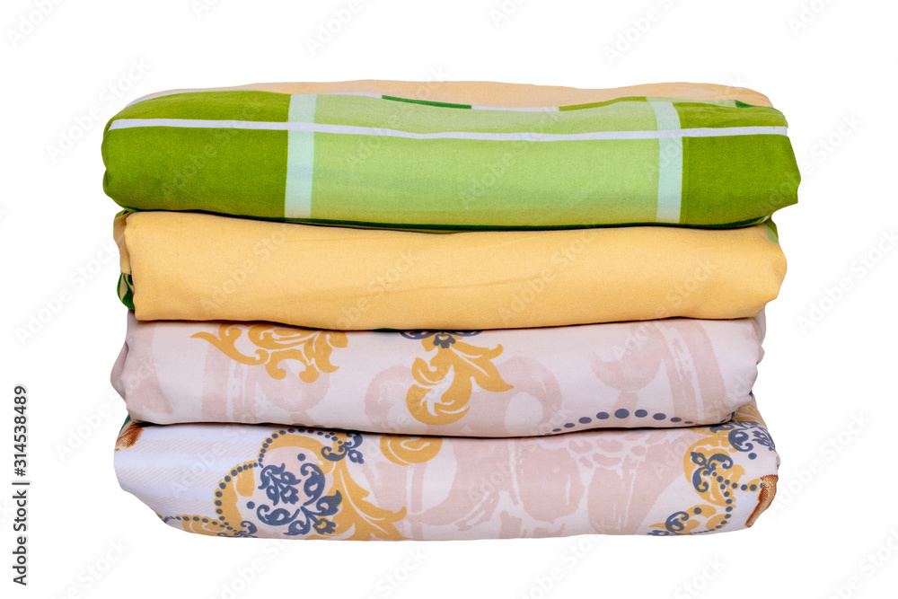 Wall mural Bed linen isolated. Close-up of a stack or pile of colorful folded bed linen or duvet covers isolated on a white background. Macro of washed and ironed fabric, useful for laundry service or textile re