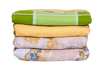 Bed linen isolated. Close-up of a stack or pile of colorful folded bed linen or duvet covers...