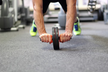 Man using abdominal roller for working out abdominals. Front view. Focus on hands.