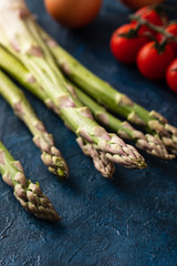 Tasty fresh vegetables for dinner or lunch ready to be cooked with ripe cherry tomatoes, lime, asparagus, eggs and olive oil.
