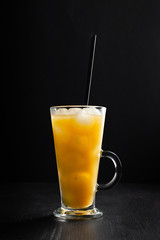  glass of fresh orange juice with ice on a black background with a place for inscription