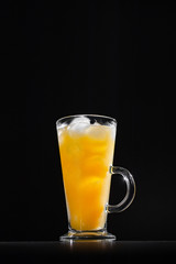  glass of fresh orange juice with ice on a black background with a place for inscription