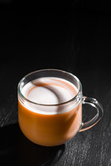  hot cocoa with milk in a transparent mug with steam on a black background with a place for inscription