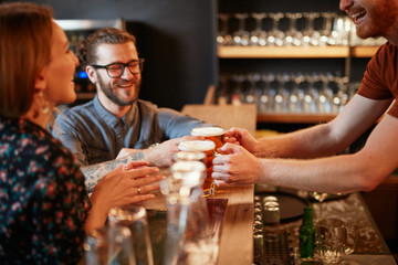 Bartender serving beer to customers. Pub interior.
