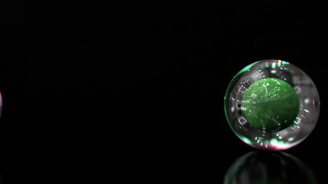 3d design of futuristic balls with transparent glass bubble around on the black background. Looped animation of rolling spheres on the floor.