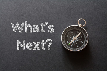 Written What's Next words on black background with compass