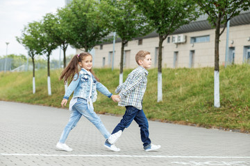 Fototapeta premium Little brother and sister walk holding hands. The concept of childhood, back to school, friendship.