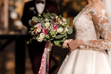 Wedding day. Groom and bride holds a bouquet of pink and white flowers. Wedding decoration.