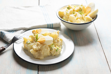 Potato salad with egg and mayonnaise on wooden background