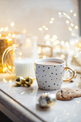 Cozy winter holiday decoration, Christmas lights and coffee cup with decor details, real home
