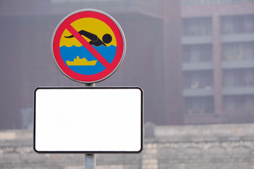 copy space, white information plate under the forbidding sign about the prohibition of swimming in the city reservoir. Water safety, prohibition signs, urban infrastructure