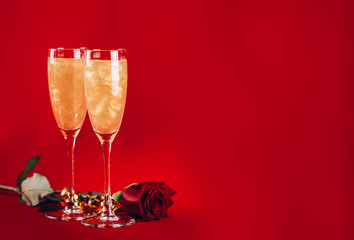 Valentines day background with shining champagne glasses and red rose on red background. And greeting card with heart.
