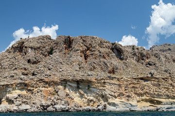 View from a motor boat on the mediterranean sea at the rocky coastline near Stegna on the eastside of Greek island Rhodes