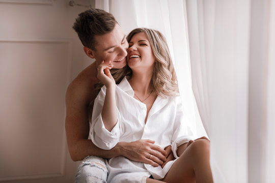 loving couple having fun together at home, playful wife biting smiling husband ear, piggyback, man and woman playing childish in bed, enjoying funny intimate moments