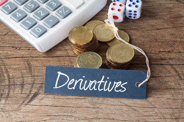 Conceptual image of the word Derivatives written on label tag with coins,dice and calculator