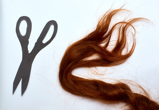 A Lock Of Red Hair On A White Background. Scissors Cut Out Of Paper. Red-haired Girl's Hair