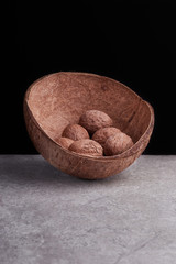 Walnuts in shell in a coconut on a marble on black background