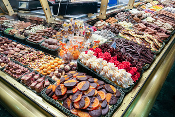A stand with a diverse assortment of sweets: chocolate, marshmallows, marmalade, orange in chocolate, cookies.