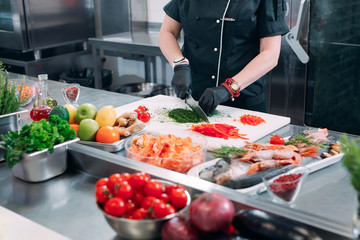 A Woman Chef cuts vegetables in the kitchen in a restaurant.