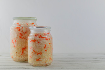 glass jars of fermented white cabbage, cucumbers, tomato, onions. vegetables on a light background. fermentation is a source of probiotic