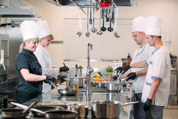 Cooks prepare meals on an electric stove in a professional kitchen in a restaurant or hotel.