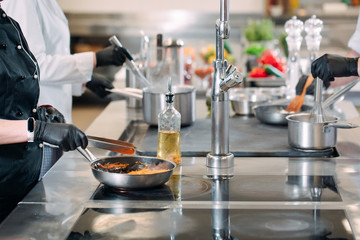 Cooks prepare meals on an electric stove in a professional kitchen in a restaurant or hotel.