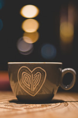Heart cup with almond cappuccino and bokeh lights