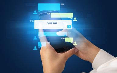 Female hand typing on smartphone with SOCIAL inscription, social networking concept