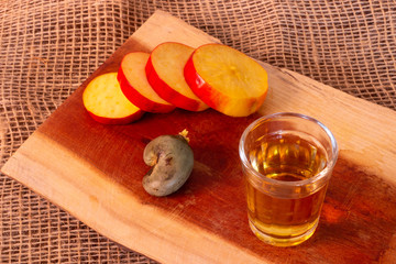 A shot of cachaca with a fresh cashew slices. best way to drink cachaca. 