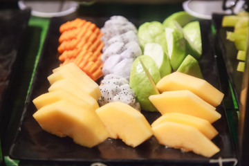 Fresh assorted tropical Asian seasonal fruits serving (guava, dragon fruit, papaya, cantaloupe) in black tray. Vegetarian and Vegan Food, Natural and Organic Fruit, Nutrition and Health care concept.