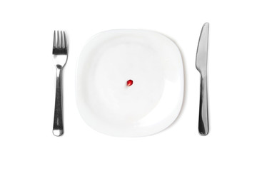 Pomegranate seed on an empty white plate. Next to the plate are cutlery. Conceptual: diet and a small amount of food. White isolated background.