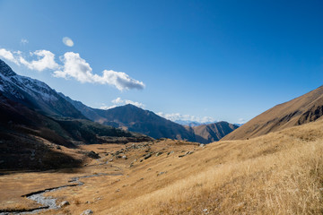 Juta trekking path landscape with river and mountains in sunny autumn day -  popular trekking  in the Caucasus mountains, Kazbegi region, Georgia.