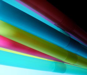 Background from multi-colored plastic cocktail tubes on a dark background