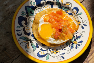 Mexican egg mounted on corn tortilla with sauce also called 