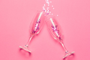 Two champagne glasses with splash of pink stars shaped confetti over pink background. Top view. Valentine's Day concept © Тетяна Шустик