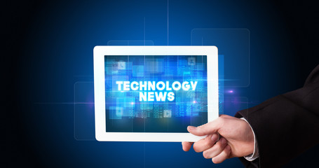 Young business person working on tablet and shows the inscription: TECHNOLOGY NEWS