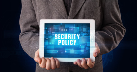 Young business person working on tablet and shows the digital sign: SECURITY POLICY