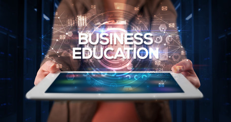 Young business person working on tablet and shows the inscription: BUSINESS EDUCATION, business...