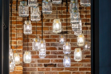 unusual lamps made of glass jars, suspended from the ceiling by black cables. interior of a...