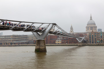 Urban view of London with Millennium bridge, St. Paul Cathedral and Thames river in a cloudy day.
