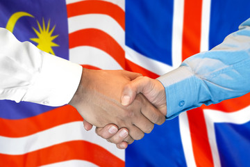 Handshake on Malaysia and Iceland flag background.
