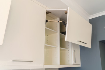 Kitchen wall cabinets with MDF facades and a folding opening mechanism in light beige.