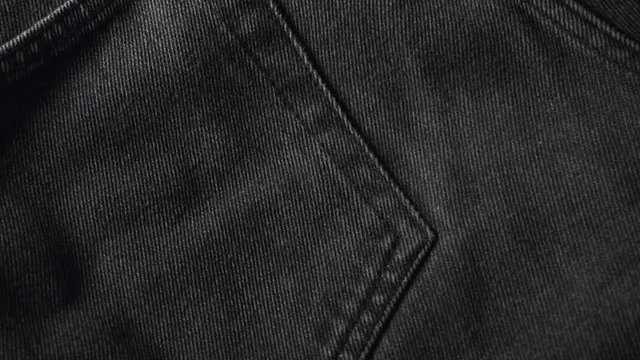 Girl touching a smooth black jeans, checking the quality of fabric in a clothing store or textile factory. High quality footage.