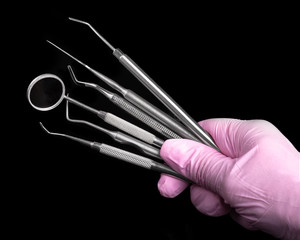 Dental instruments in hand in a pink glove on a black background. Dental clinic hygiene